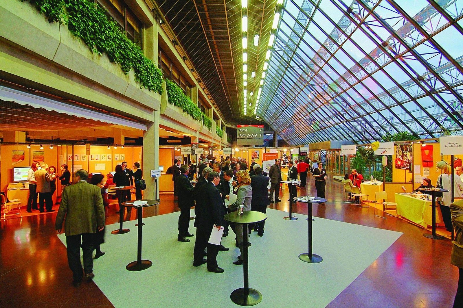 Visiteurs et exposants dans la galerie vitrée d'un parc des expositions, type de salon desservi par nos navettes à Villepinte
