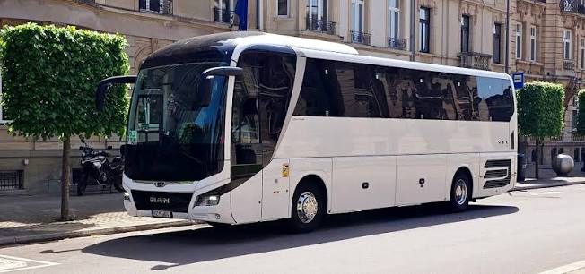Autocar de tourisme blanc garé dans une rue bordée d'arbres, pour déposer un groupe au pied de la butte Montmartre