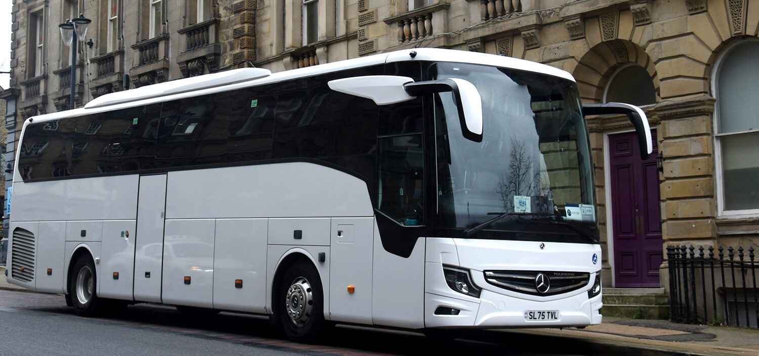 Autocar grand tourisme blanc stationné le long d'une rue, prêt pour une visite de groupe dans le 7e arrondissement de Paris