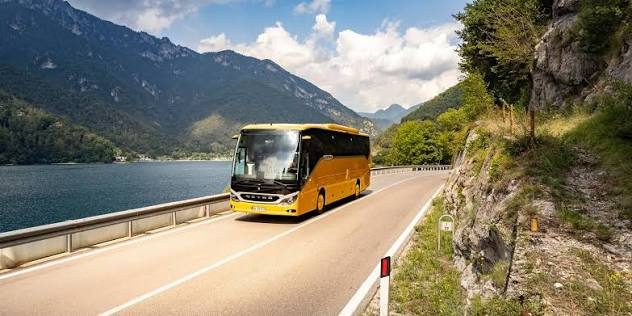 Autocar jaune sur une route en bord de lac, pour les navettes de groupes vers les salons de Paris Nord Villepinte