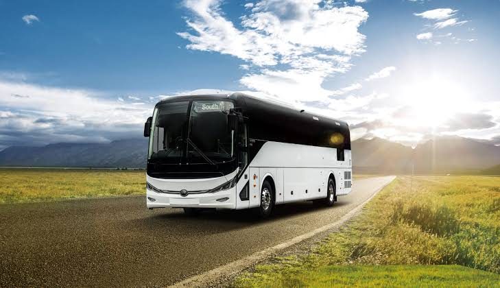 Autocar de tourisme blanc et noir sur une route de campagne, pour une excursion de groupe au départ d'un hôtel du 9e