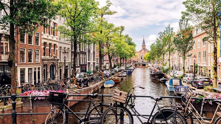 Canal d'Amsterdam bordé de maisons typiques et de vélos, destination d'un voyage Paris Amsterdam en bus avec chauffeur